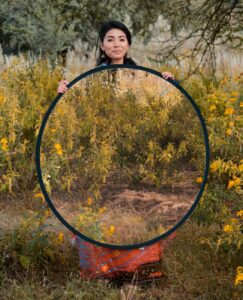 smiling ethnic woman with big mirror in nature