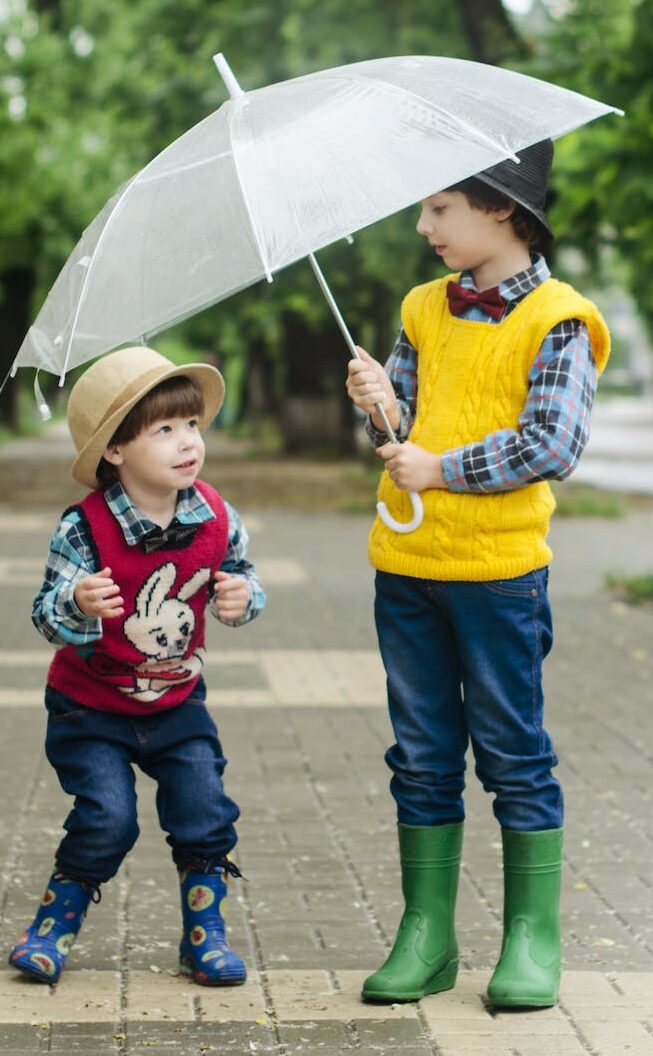 toddler holding umbrella beside girl